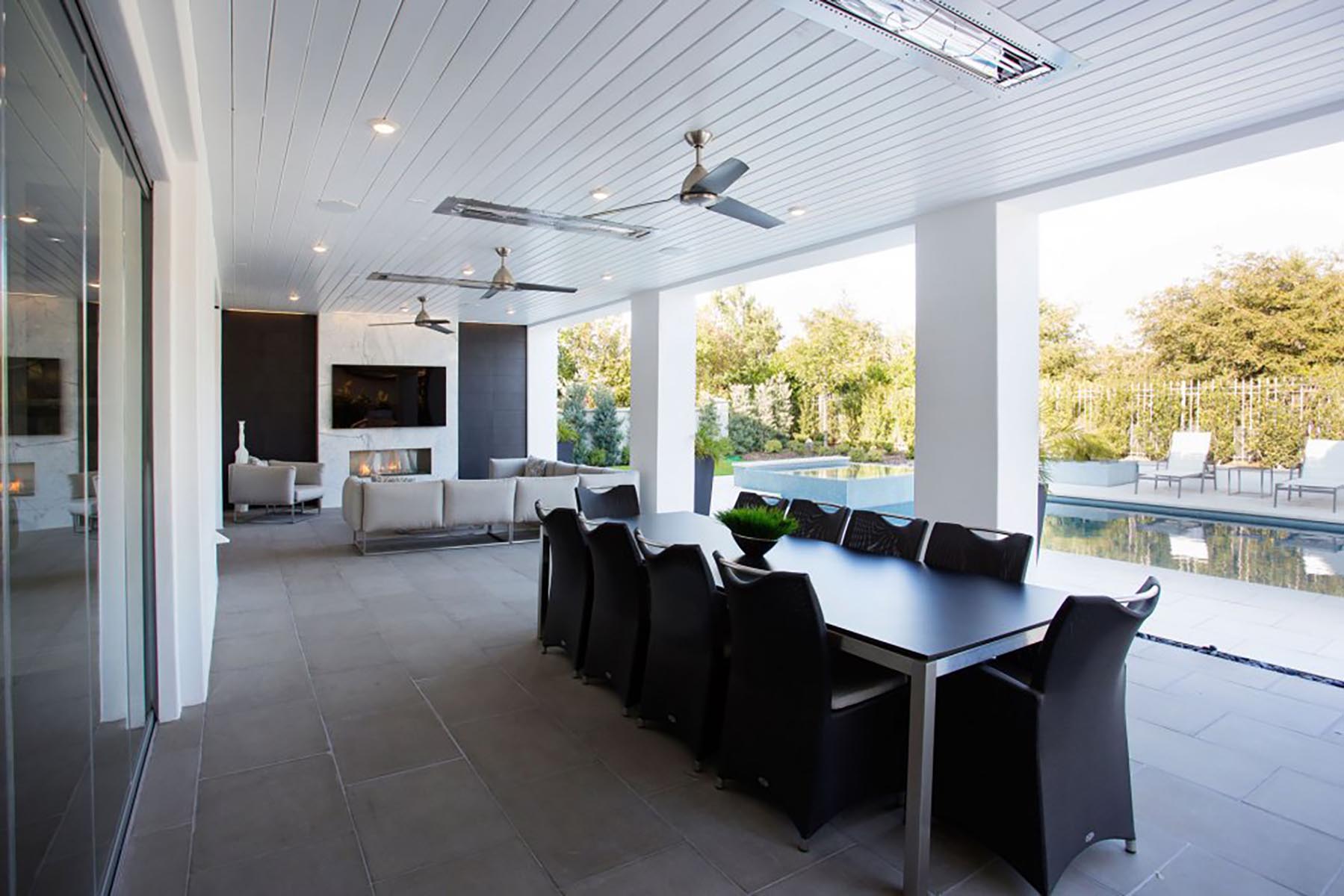 An outdoor home addition with a dining table near a swimming pool