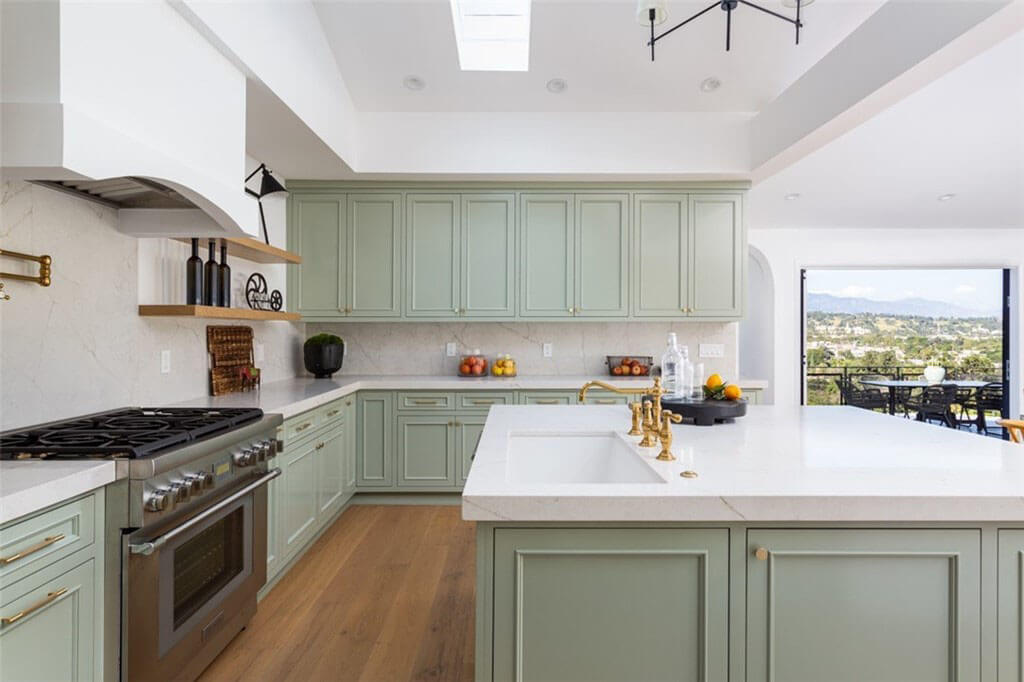 Kitchen area with pale green cabinets and large window opening
