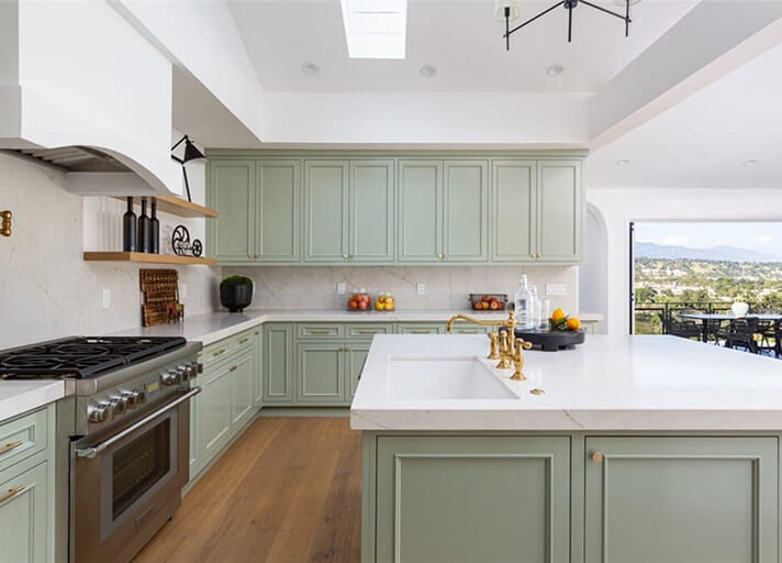 Kitchen area with pale green cabinets and large window opening