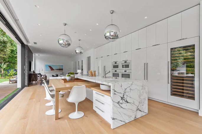 a modern white kitchen with a waterfall countertop island