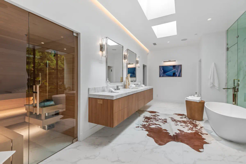 a modern bathroom with a double sink, a sauna, and a standing tub