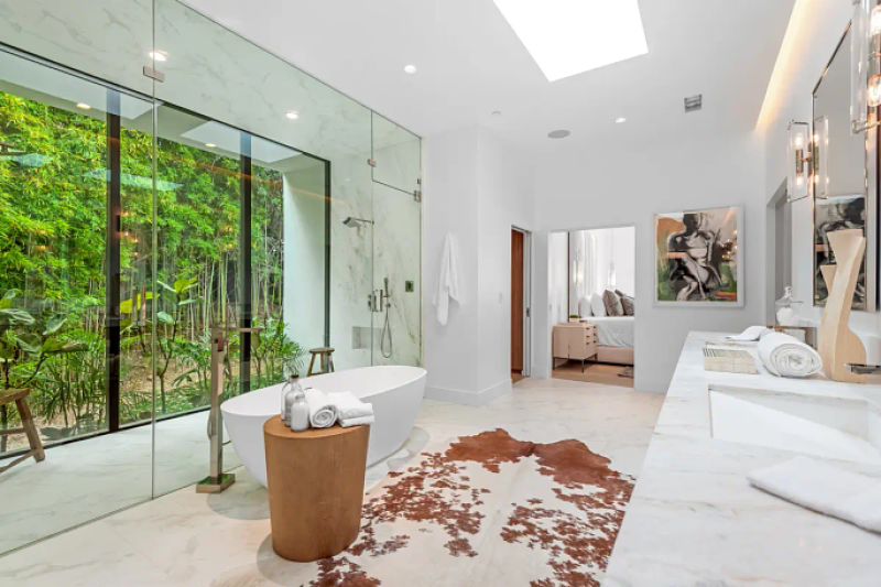 a modern bathroom with a large glass shower and floor-to-ceiling windows