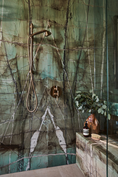 a green marble shower with bronze fixtures