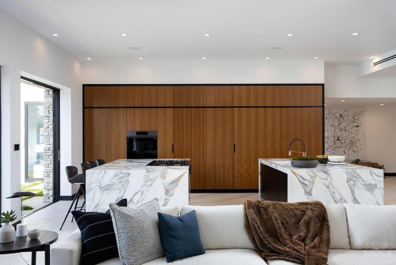 a modern kitchen with waterfall countertops and hidden appliances