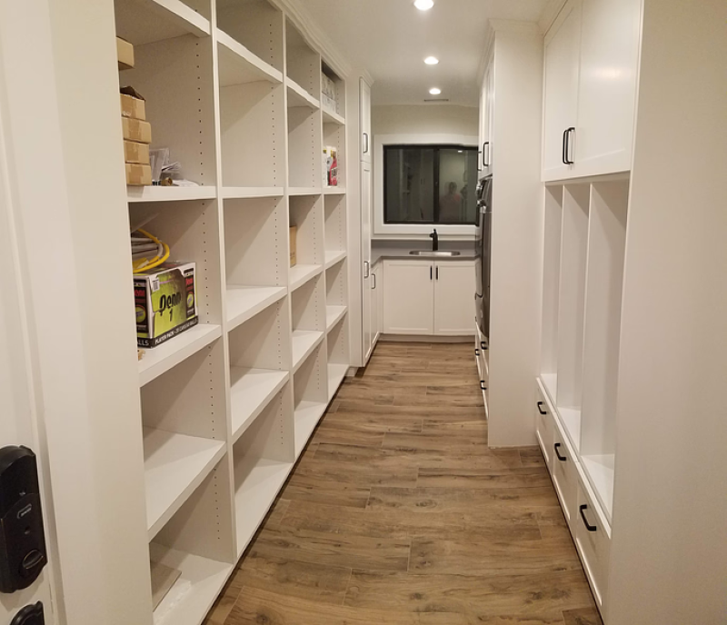 a laundry room mudroom with white shelving and wood flooring