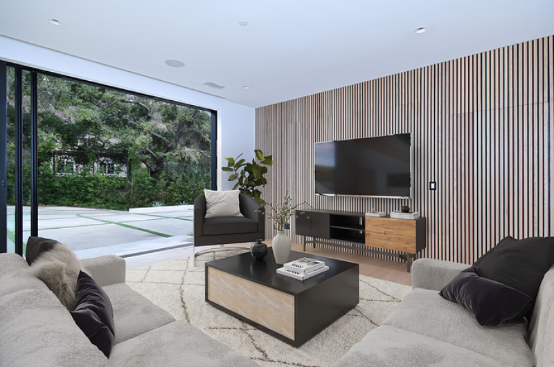 a modern living space with an open glass door and a fluted wood accent wall