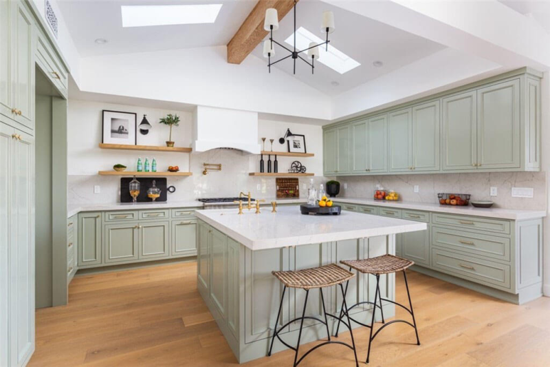 a pastel green kitchen with an island and white countertops